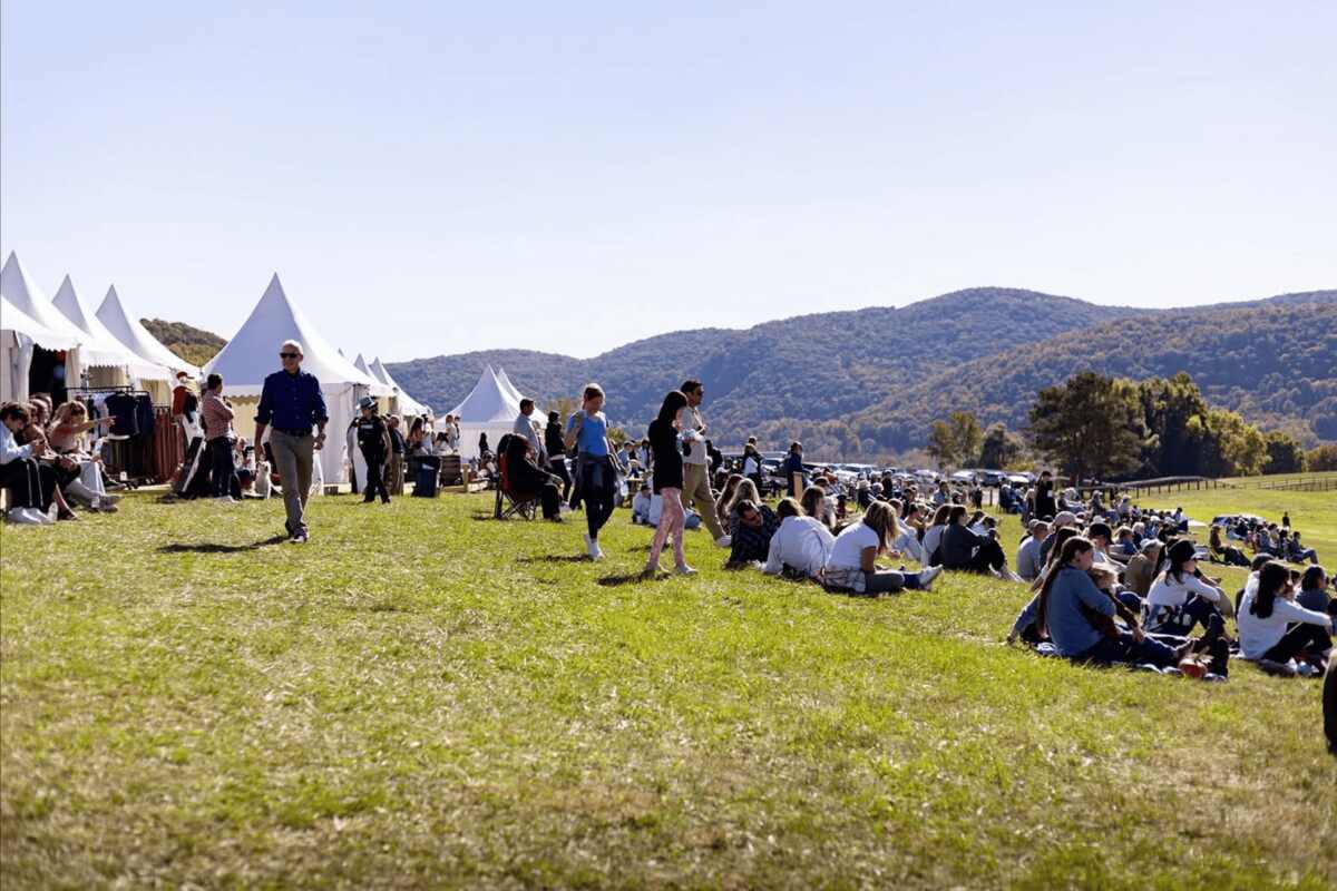 Spectators sitting in grass next to vendor tents