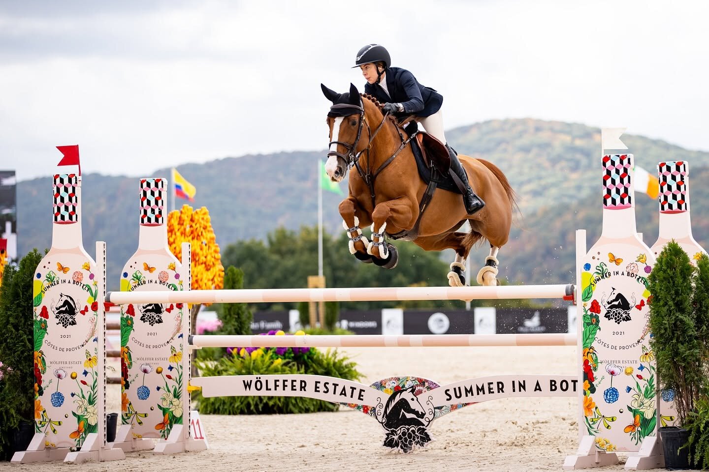 Horse and rider jumping bright oxer with Wolffer estate decoration
